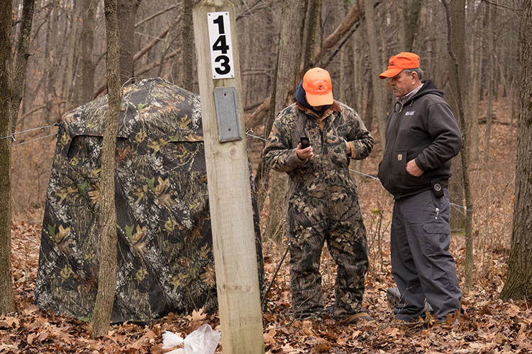 Addison Oaks County Park groundskeeper Steve Wolgast assists a managed hunt volunteer in setting up a blind at a campsite. Photo by Nina Ignaczak.