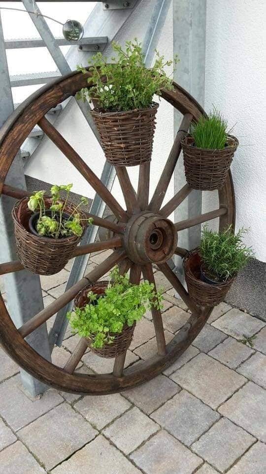 A wooden wheel with attached baskets holding plants for sale at Vintage Garden in Mt. Clemens.