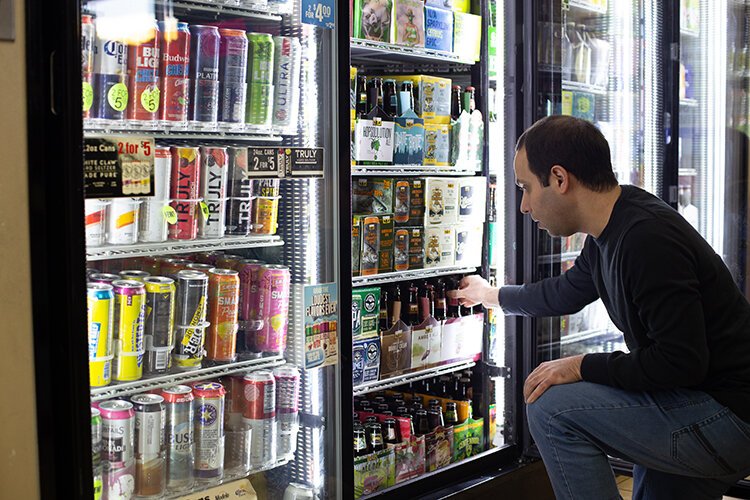 Anthony Panos carefully selects beverage options for the Shell gas station in downtown Lake Orion. Photo: Joe Powers.