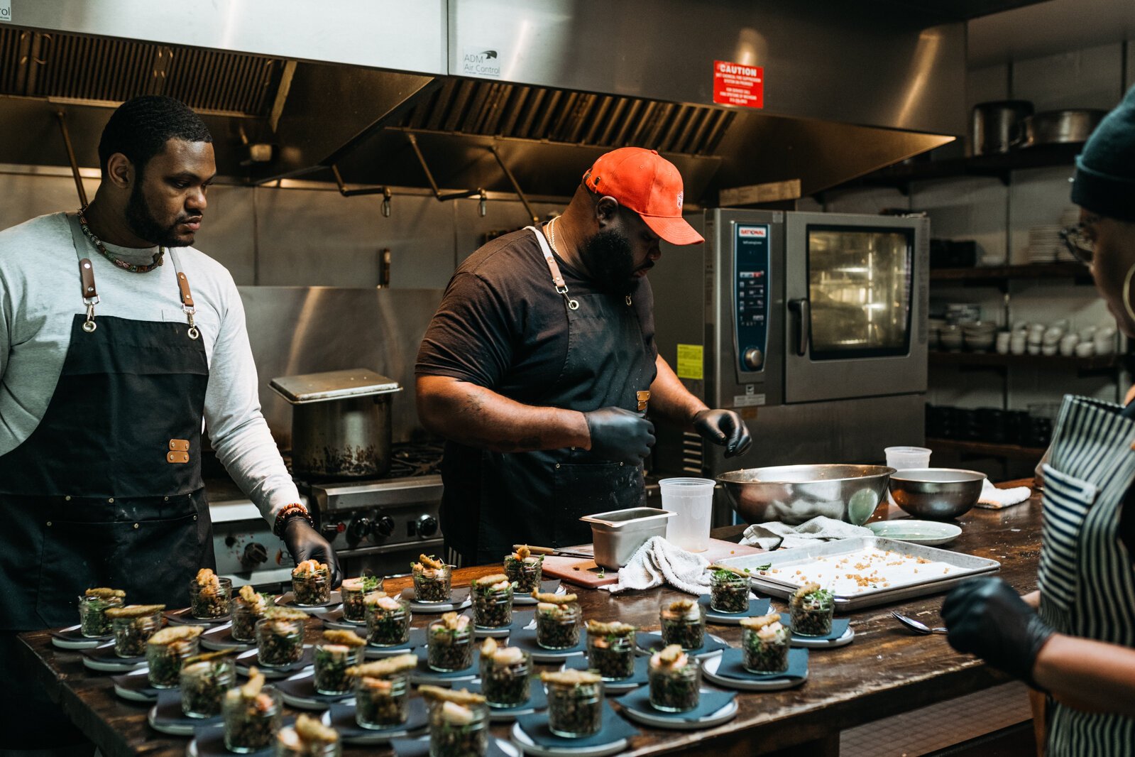Taste the Diaspora Detroit co-founders Ederique Goudia, Jermond Booze, and Raphael Wright prepare dishes at Frame as featured chefs.