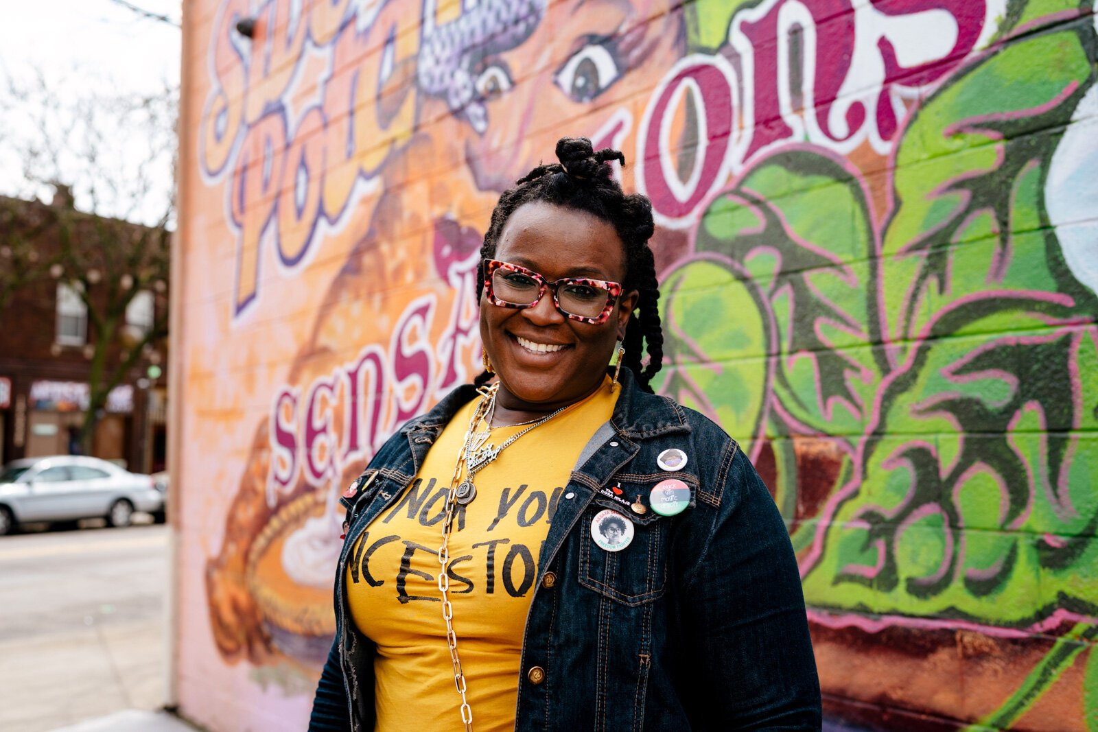 Espy Thomas in front of the mural outside Sweet Potato Sensations.