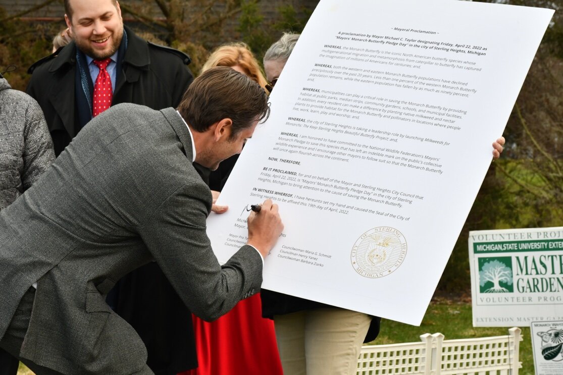 Mayor Taylor signs a proclamation acknowledging the Mayors’ Monarch Pledge.