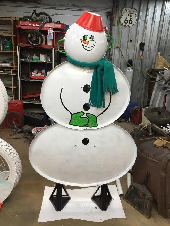 This new sculpture in downtown Northville includes two satellite dishes, the face is a wok, the hat a metal planter, and the boots are car jacks.