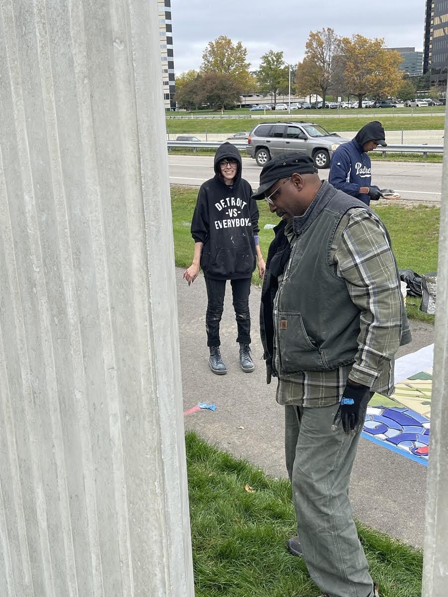 Muralist Hubert Massey (foreground) inspects the work on his art installation at Lawrence Technological University.
