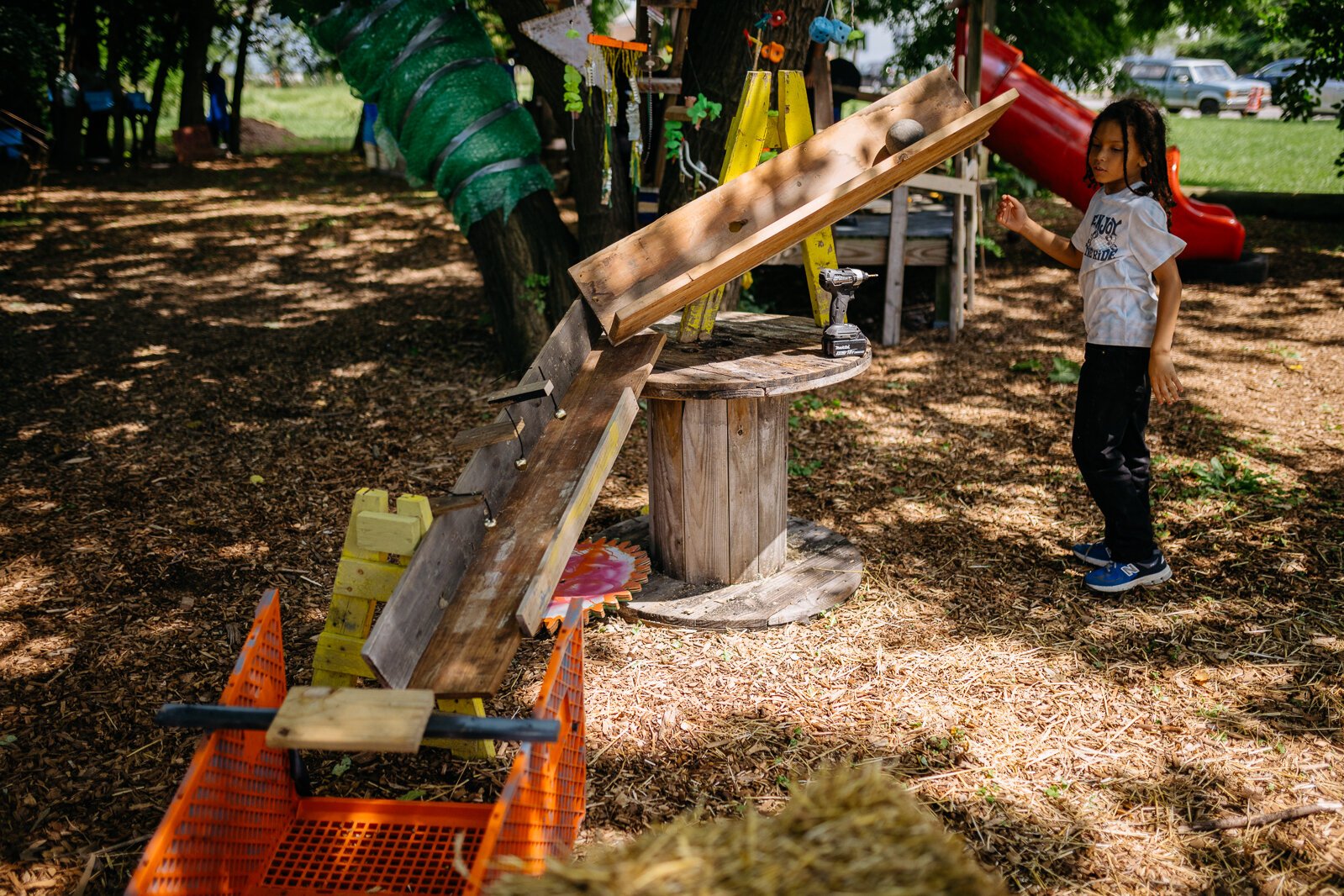 A Camp Carpenter participant rolls a bocce ball down a Rube Goldberg machine created by campers.
