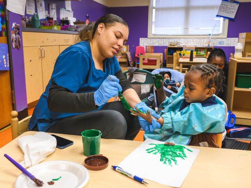 Teacher helping child at NEST Child Care and Parent Institute in Detroit